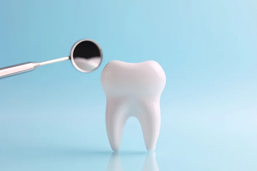 crowns-in-seneca-tooth-model-beside-a-dental-mouth-mirror-on-a-blue-background (1)